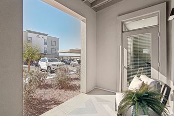 A patio with a chair and a door to a parking lot